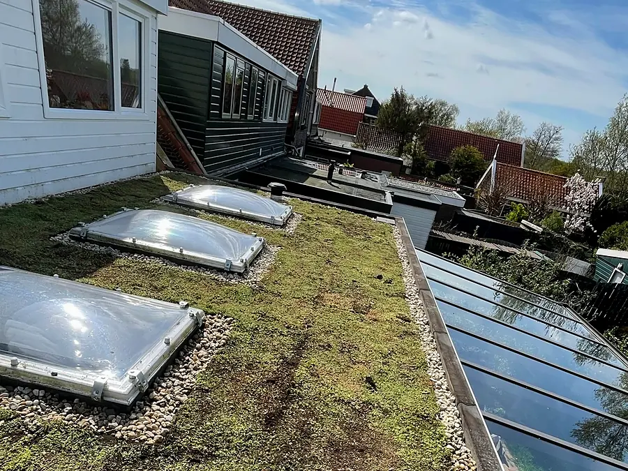 Sedumdak met drie lichtkoepels naast een glazen overkapping
